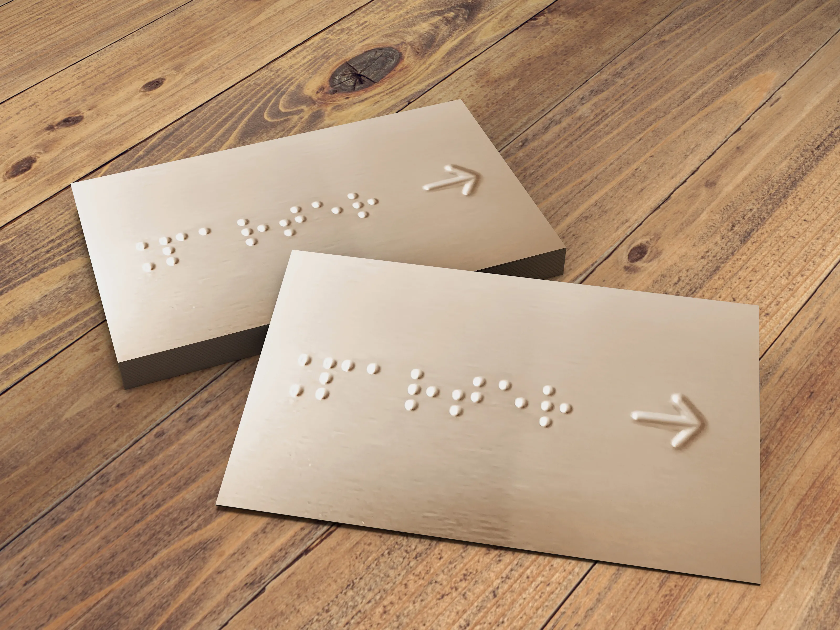 Tabliczka stalowa z tekstem w alfabecie Braille’a wraz z wytłoczoną strzałką w prawo.